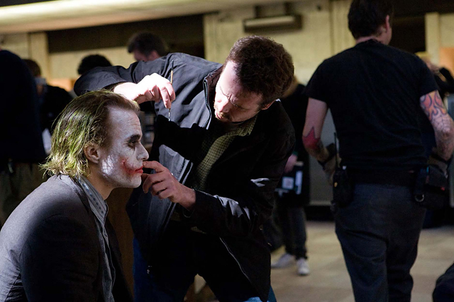 Prosthetics makeup supervisor Conor O’Sullivan adjusts Ledger’s prosthetic scars on location in Chicago. © Warner Bros. Entertainment Inc