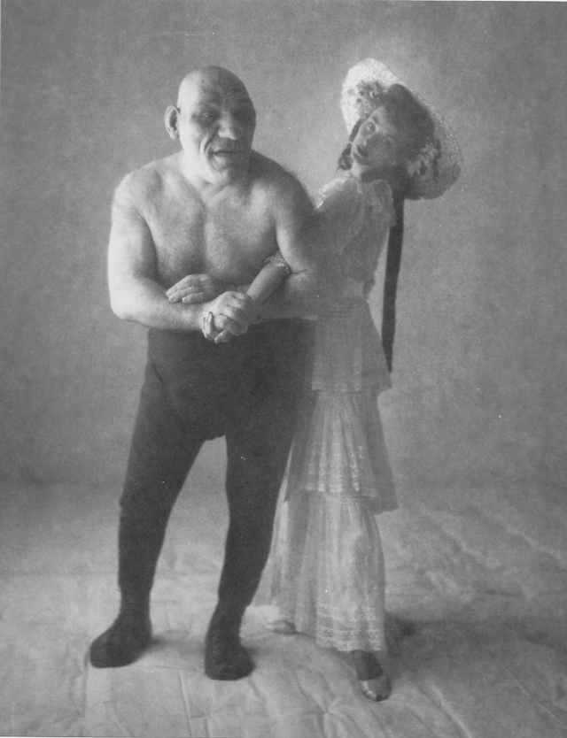 « Le lutteur, l’Ange, avec le mannequin professionnel Dorian Leigh », vers 1958, Tirage argentique d’époque, contrecollé sur carton • Etiquette "The Wrestler, The Angel with Profesional Model, Dorian Leigh”, tampons • Copyright The Conde Nast Publications et "Photograph by Penn" au dos du carton • 23,6 x 18,5 cm © Irving Penn « Le lutteur, l’Ange, avec le mannequin professionnel Dorian Leigh », vers 1958, Tirage argentique d’époque, contrecollé sur carton • Etiquette "The Wrestler, The Angel with Profesional Model, Dorian Leigh”, tampons • Copyright The Conde Nast Publications et "Photograph by Penn" au dos du carton • 23,6 x 18,5 cm © Irving Penn